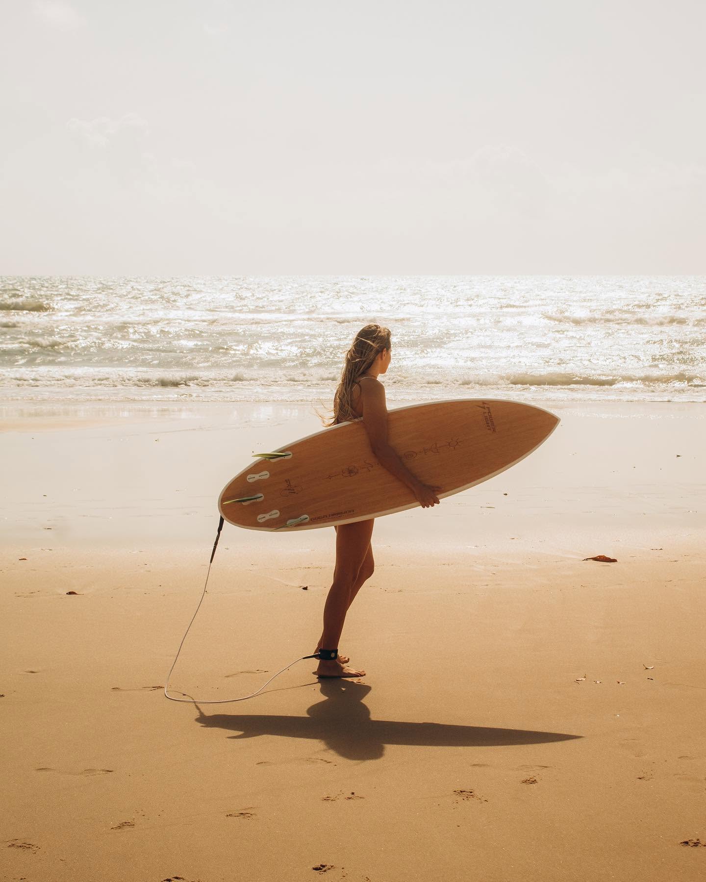 Aluno segurando prancha de surf na praia